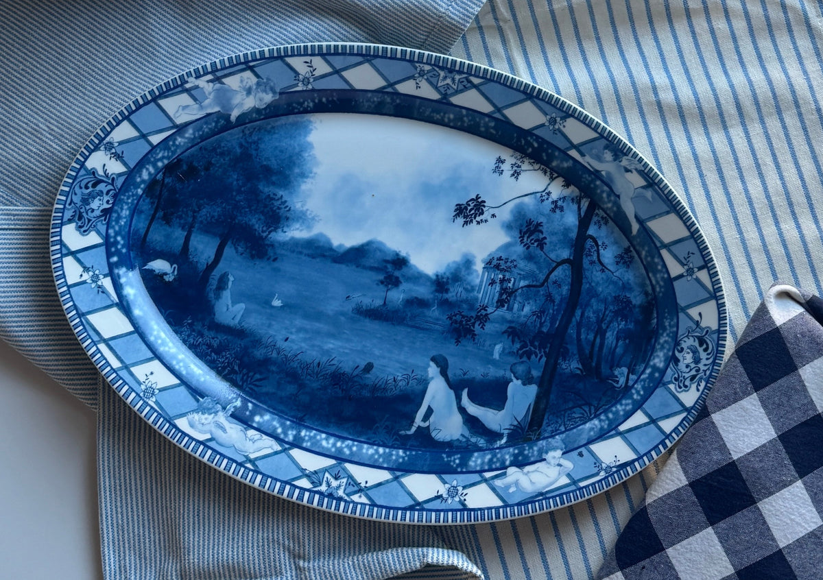 A blue and white porcelain serving dish with a floral pattern, displayed on a striped tablecloth.